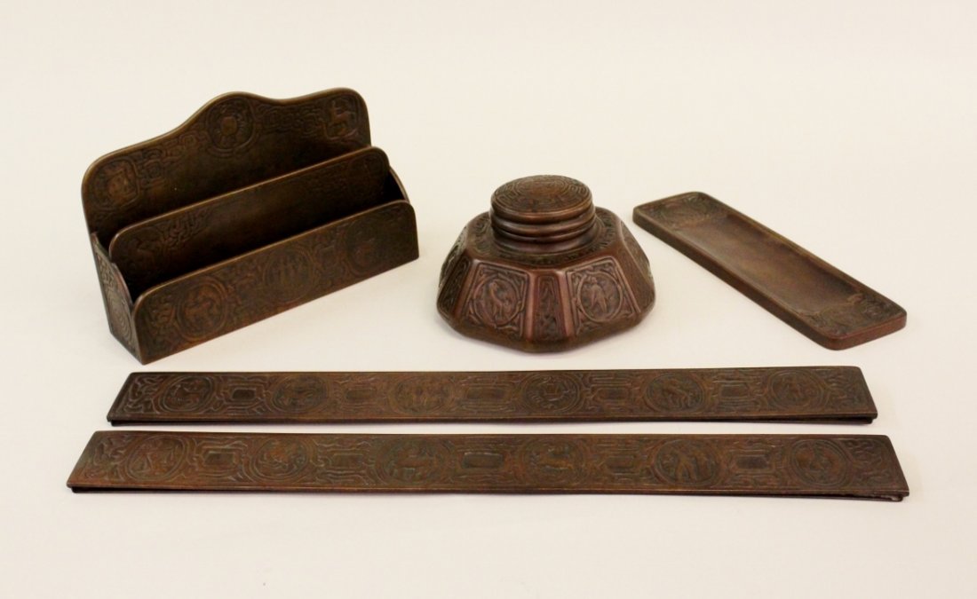 Tiffany Studios Cast Bronze "Zodiac" 5 Piece Desk Set: Signed and with dark brown patina, consisting of an inkwell, pen tray, a letter holder and pair of blotter ends, early 20th C. - Inkwell #1072: 4"H x 6 1/2" in diameter at base, Pen Tray #1000: 10"lon