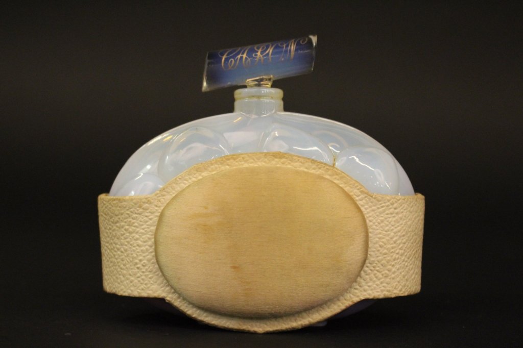 French Art Glass Perfume Bottle: Early 20th century French art glass perfume bottle for Caron," VOEU DE NOEL", blue opalescent double flower form, 1/3 full, with original satin and white leatherette collar stand 4" wide by 3 1/2" hig