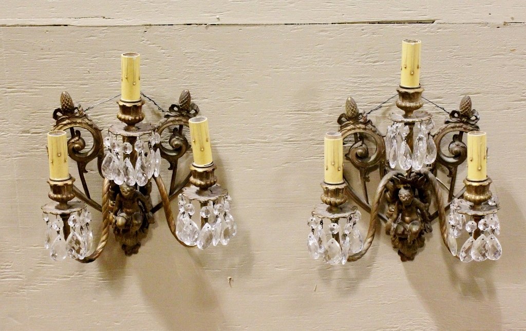 Pair of French Cherub Sconces: Sconces in stylized heart shape with flowing ribbons and a cherub. Three armed light sockets. Each decorated with clear crystals. 11.5"H x 9"W overall. Provenance: A Fine Atlanta Estate.