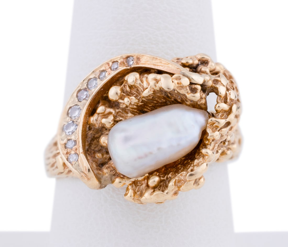 14K Yellow Gold, Pearl and Diamond Ring: Featuring a central elongated baroque white pearl within a freeform yellow gold textured setting accented by a crescent of nine petite round cut diamonds. Stamped '14K'. Approximate dimensions: Ring s