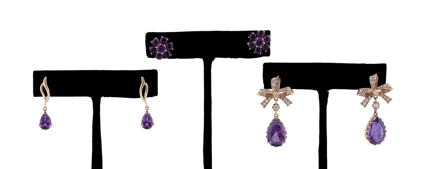 Three Pairs of 14K Yellow Gold and Amethyst Earrings: Including a pair of cluster stud earrings composed of seven prong set round cut amethysts, one pair of drop style earrings featuring a prong set pear shaped amethyst suspended from an elongated openwo