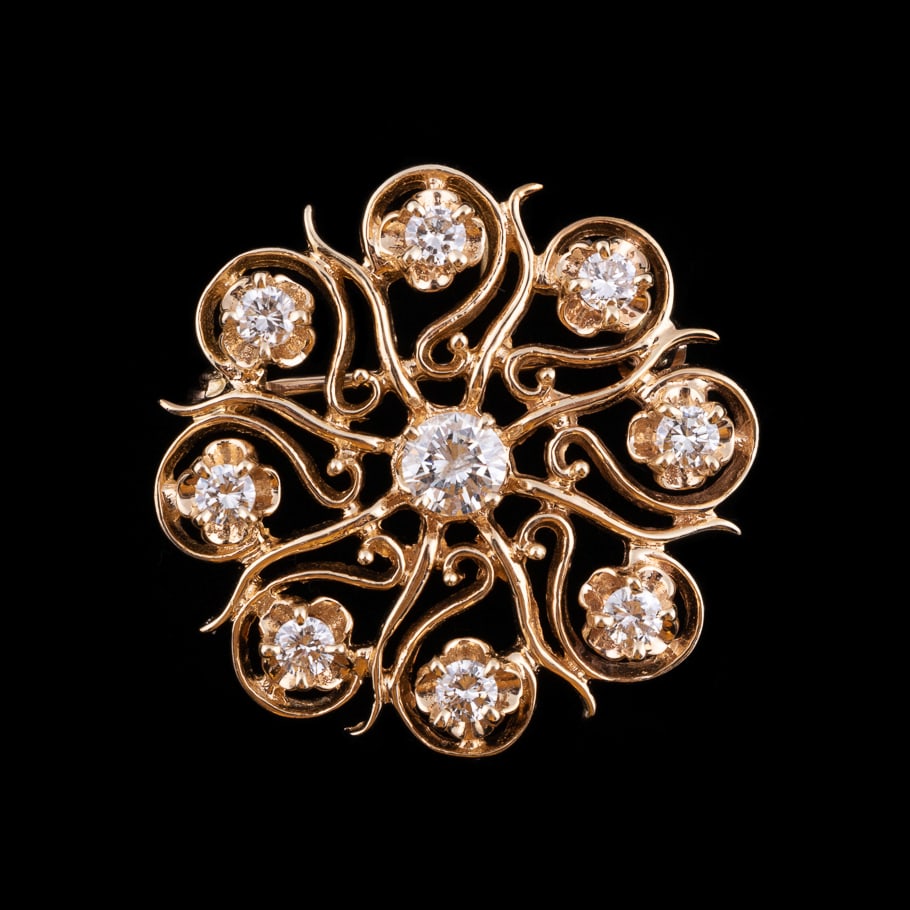 14K Yellow Gold Starburst Brooch: Featuring a central round brilliant cut diamond and eight surrounding round brilliant cut diamonds in open scrolling design. Total overall diamond weight approximately 1.25 carats. Approximate dimensi