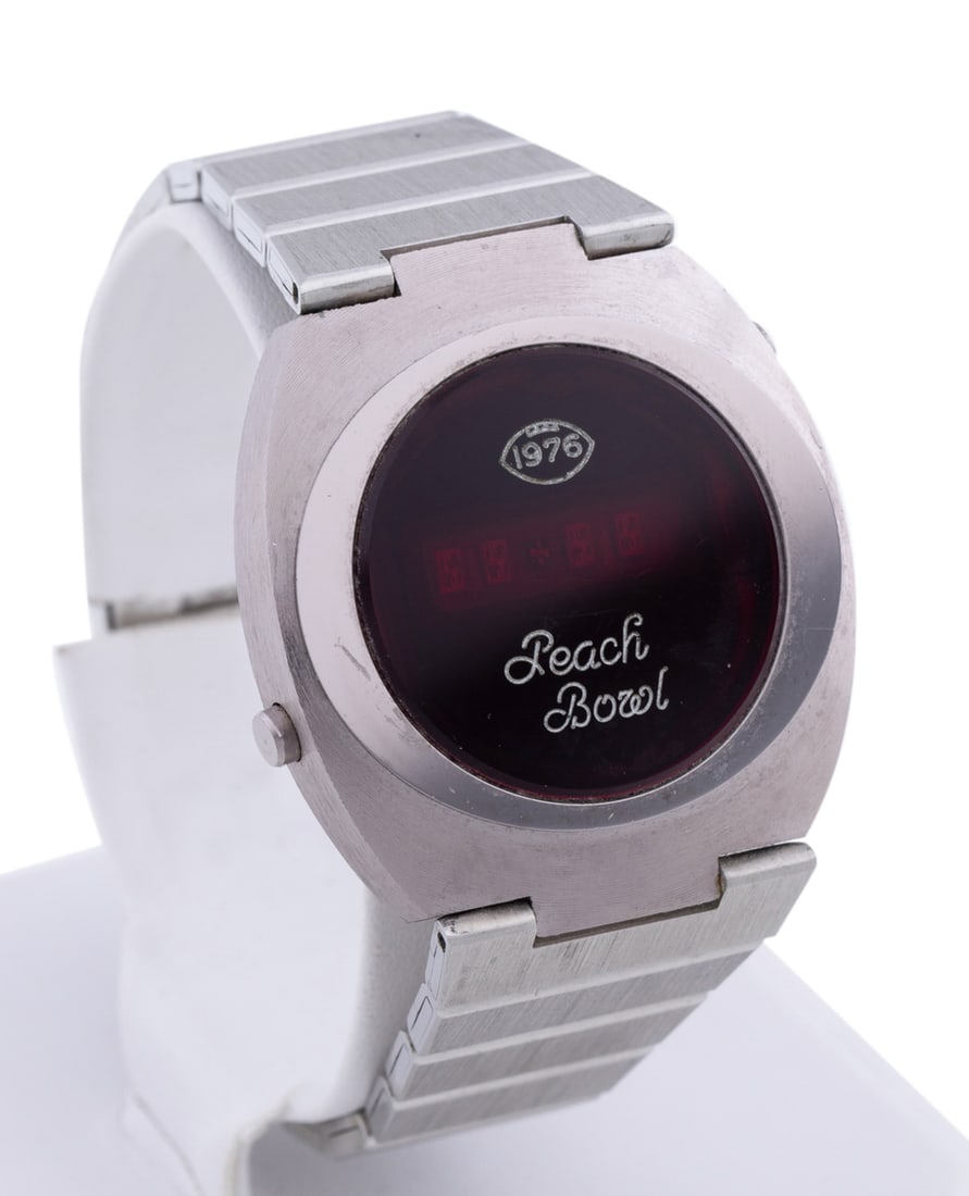 Croton, 1976 Peach Bowl Digital Wrist Watch: In stainless steel with a link bracelet. Clasp marked "Croton". Approximate dimensions: Case: h. 41mm (lug to lug) w. 37mm, Bracelet: interior circum. 7 in. Other Notes: The 1976 Peach Bowl, held at