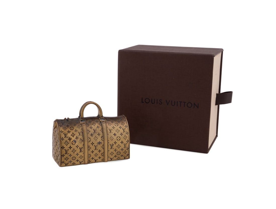 Louis Vuitton Miniature "Keepall" Paperweight: Louis Vuitton (French, founded 1859), early 21st century. Gilt metal paperweight modeled as a duffle bag, in branded box. Appropriately marked. Approximate dimensions: 2 x 2 3/4 x 1 1/4 in. (5.1 x 7 x