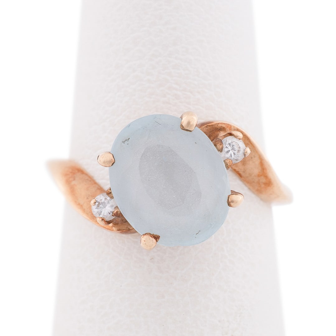 14K Yellow Gold, Aquamarine and Diamond Ring: Centering on an oval cabochon aquamarine weighing approximately 3.0 carats, flanked on either side by a petite round cut diamond weighing approximately .03 carats. Stamped '14K'. Approximate dimension