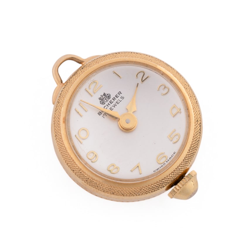 Bucherer, 14K Yellow Gold Pendant Watch: Circular case, white enamel face with Arabic numerals, engraved 14k yellow gold case, mechanical movement, reverse of open-work skeletonized movement. Approximate dimensions: Diameter: 3/4 in. Dial: 1