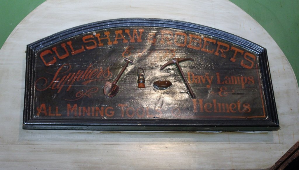 "Culshaw and Roberts Mining" Sign: Vintage black wooden advertisting sign with painted text reading "Culshaw & Roberts, Supplies, All Mining Tools, Davy Lamps & Helmets". Sign with arched top. 16"H x 33"W