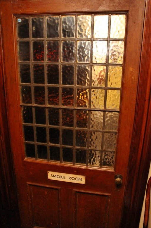 Antique Smokeroom Entryway Door: A nice hardwood 2 panel door with a leaded glass window comprised of 49 small panes of glass. Bears a plaque that says "Smoke Room" 88 1/2"H x 45"W