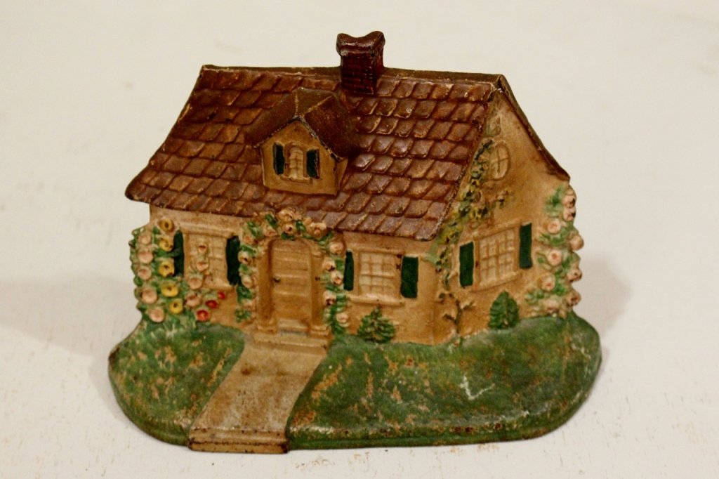 A Painted Cast Iron Doorstop: In the form of a small cottage.