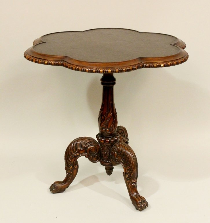 Side Table with Scalloped Edge: Occasional table with metal top inset in a wooden frame. Top decorated with scrolled foliates. Table raised on a three legs on lion's paw feet. Height 24.5 inches. Diameter of top 26.5 inches.