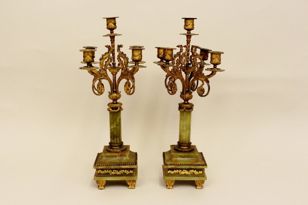 Pair of Gilt and Alabaster Candelabra: Two green alabaster and gilt metal candelabra with scrolled foliate decoration above fluted column form. Each raised on a square base decorated with a band of grapes and grapevine imagery. Each candel
