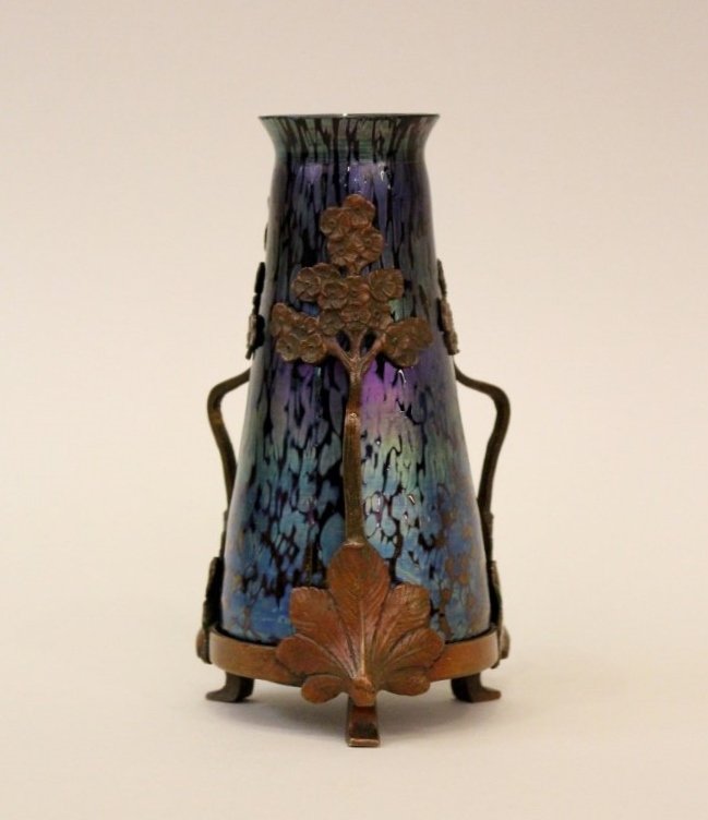 Art Nouveau Loetz Vase: Iridescent blue Loetz table vase with bronze mounting in the form of a tree terminating at base of the trunk with a stylized leaf form. Mount with two handles and circular base raised on three feet. U