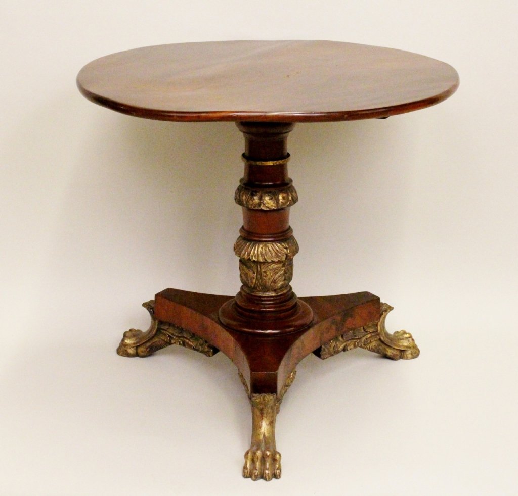 E. 19th C. Parcel Gilt Mahogany Stand: Parcel gilt mahogany tilt top stand in classical style with round top on turned and acanthus carved pedestal with tripartite base raised on animal's paw feet. Height 28 inches. Diameter 29.5 inches.