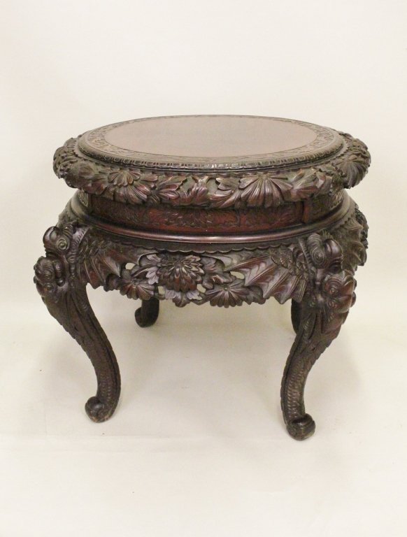 E. 20th C. Chinese Carved Teak Table: Of round form and heavily carved with floral border and skirt on four carved winged serpent/dragon legs. Height 31.5 inches, width 42 inches.