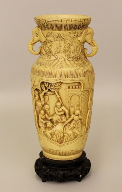 Oriental Table Vase: Table vase (NOT IVORY) with two medallions with figural decoration below stylized wave and sun decoration between two elephant head handles. Vase raised on ebonized wood oval stand. Marked with charac