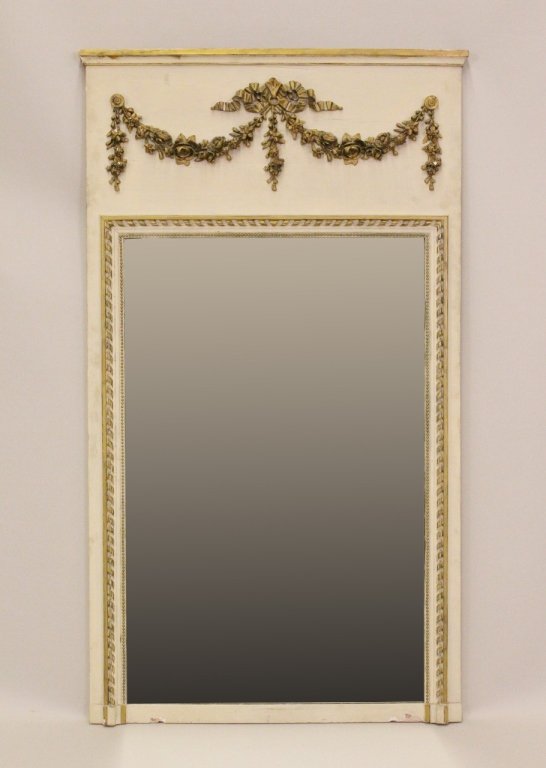 Wood and Gilt Accented Trumeau Mirror: Rectangular vertically-aligned wall mirror with cream colored painted finish and gold painted floral swag accents at top. Gold painted banding at top and around mirror. 56.5 inches x 32.5 inches.