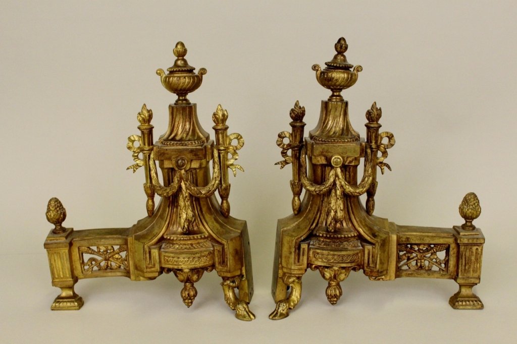 Pair of Brass Andirons: Andirons with architectural form with an urn atop a pedestal with ribbon, swag, foliate and acorn decoration. Height 13 inches, width 9.5 inches, depth 3 inches.