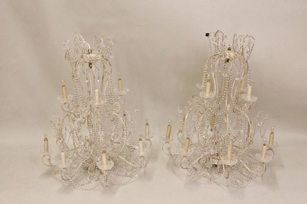 Pair of Clear Beaded and White Metal Chandeliers: Two matching hanging chandeliers with white metal frame with vintage patina. Each with four electrified lights at top above eight electrified lamps. Decorated with draped clear round beaded strands an