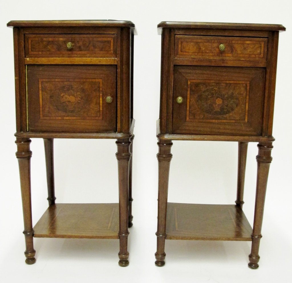 Pair of French Walnut Stands: Each walnut wood stand with one drawer over one swing front door on four turned tapered legs. Doors and drawers decorated with banded inlay surrounding a burled walnut panel with an inlaid basket of f