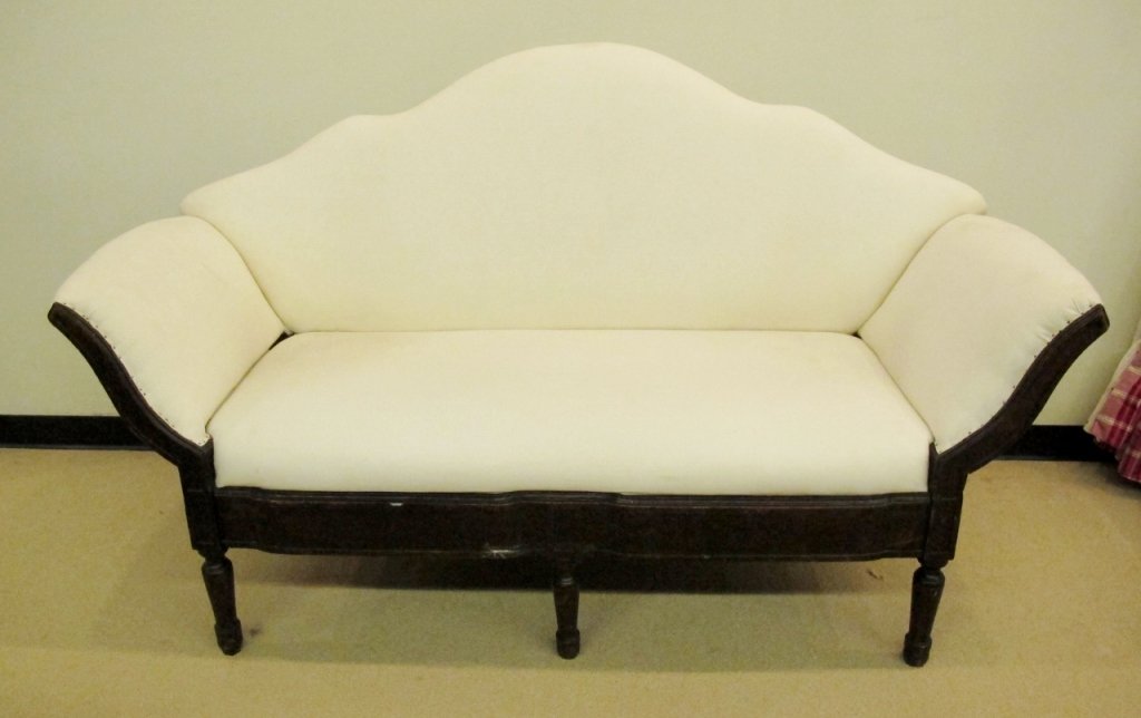 19th C. Stained Wood & Off-White Settee: 19th century. Settee with carved and stained mahogany frame raised on five turned wood legs. Settee with arched back and splayed arms covered in off white to cream colored fabric upholstery. Height 42