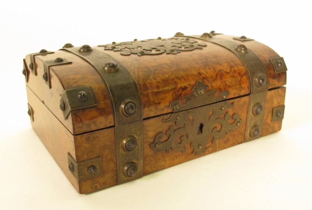 Burled Wood & Metal Mounted Box: Late 19th/Early 20th century. Lidded dresser box composed of burled wood and with metal mounts throughout with scrolled foliate decoration on top and front surrounding escutcheon. Metal banding with d