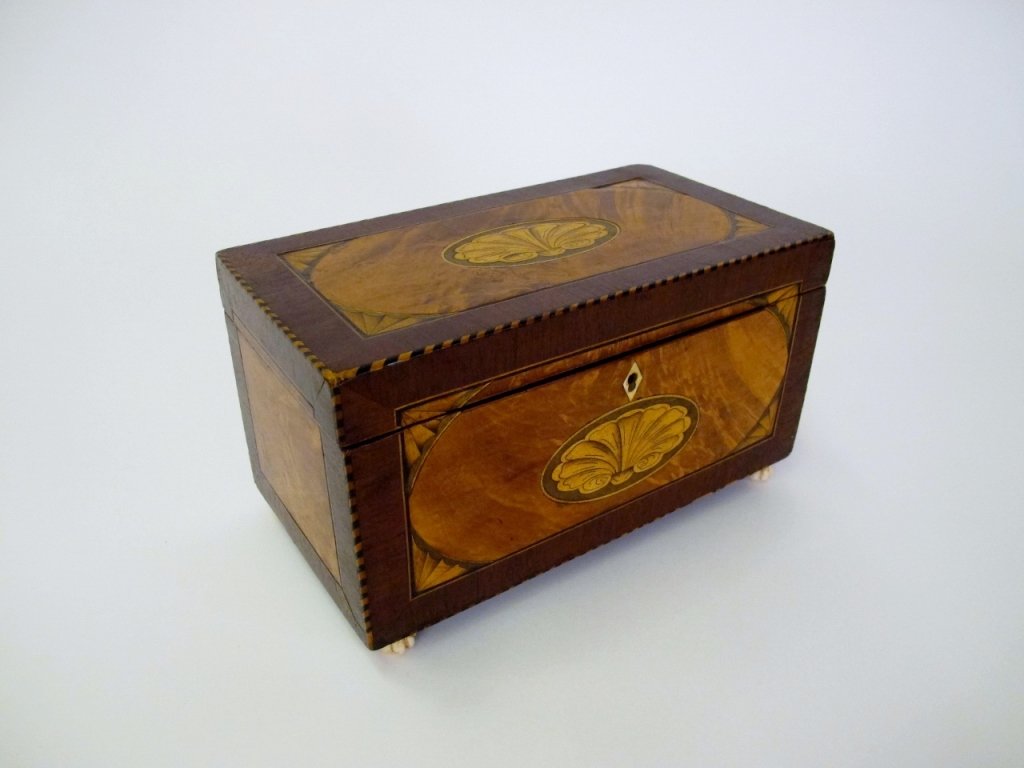 19th C. Inlaid Tea Caddy: English, 19th century. Wooden rectangular tea caddy with inlaid shell decoration in oval medallion on top of hinged lid and front of storage box. Box with additional decoration in corners of top and f