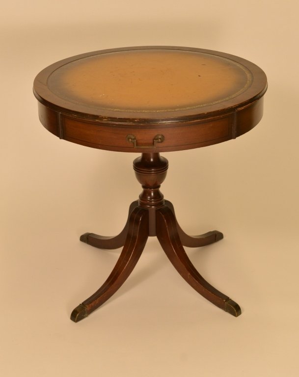 Circular Mahogany Drum Table: Circular mahogany wood drum table with inset brown leather top with gilt accented border on top above pedestal form base with four splayed legs with metal capped feet. Height 27.5 inches, diameter of 