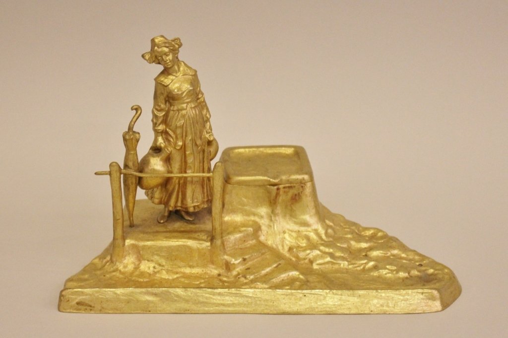P. Tereszczuk Figural Inkwell: Peter Tereszczuk (Ukrainian/Austrian 1875 -1963), Vienna. Gilt metal inkwell with traditionally costumed woman in hat and collared dress carrying two large handled water jugs in each hand. Her sun par