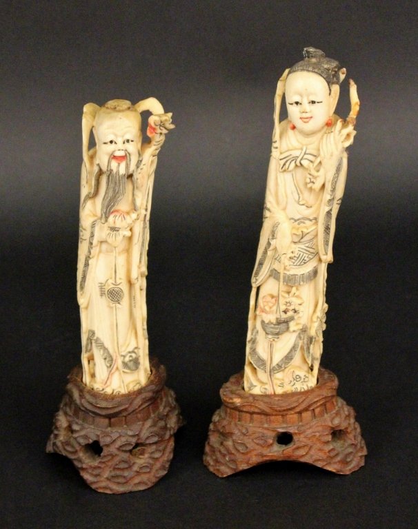 Two Chinese Carved Ivory Figures: Two Chinese carved ivory figures raised on wooden oval bases. One depicting an older man with a long dark beard wearing long robes and holding an cane with an animal's head at top, presumably a sage f