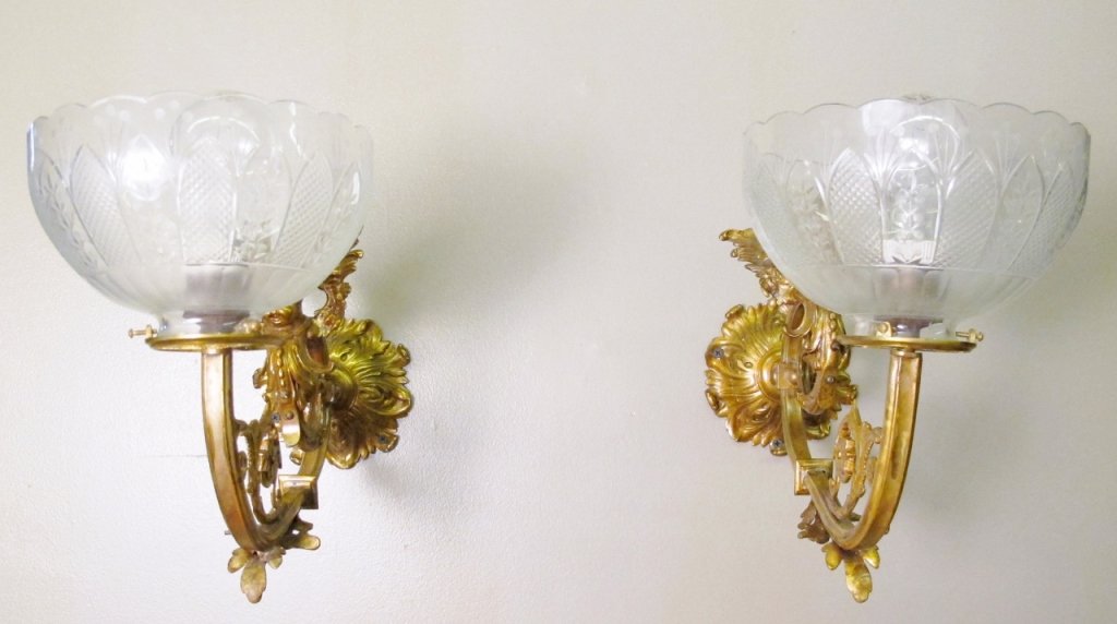 Pair of Victorian Metal & Glass Wall Sconces: Two matching decorative Victorian wall sconces with metal scrolled foliate, winged cherub and floral decoration on copper tone finished metal leading to an electrified light socket within molded glass