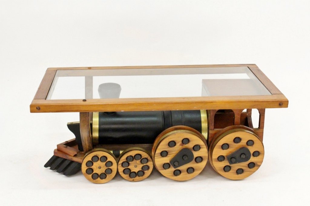 Train Motif Oak & Glass Coffee Table: Unique and whimsical coffee table with rectangular glass top framed in stained oak wood above a steam engine base with eight wheels with black painted circular spokes. Train accented with brass metal