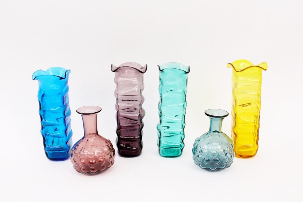 Group of Six Blenko Art Glass Vases: Group of six Blenko modern art glass vases including four table vases of matching tall rippled panelled shaft form with ruffled rim (in marigold yellow, purple, marine blue, and teal green glass) and