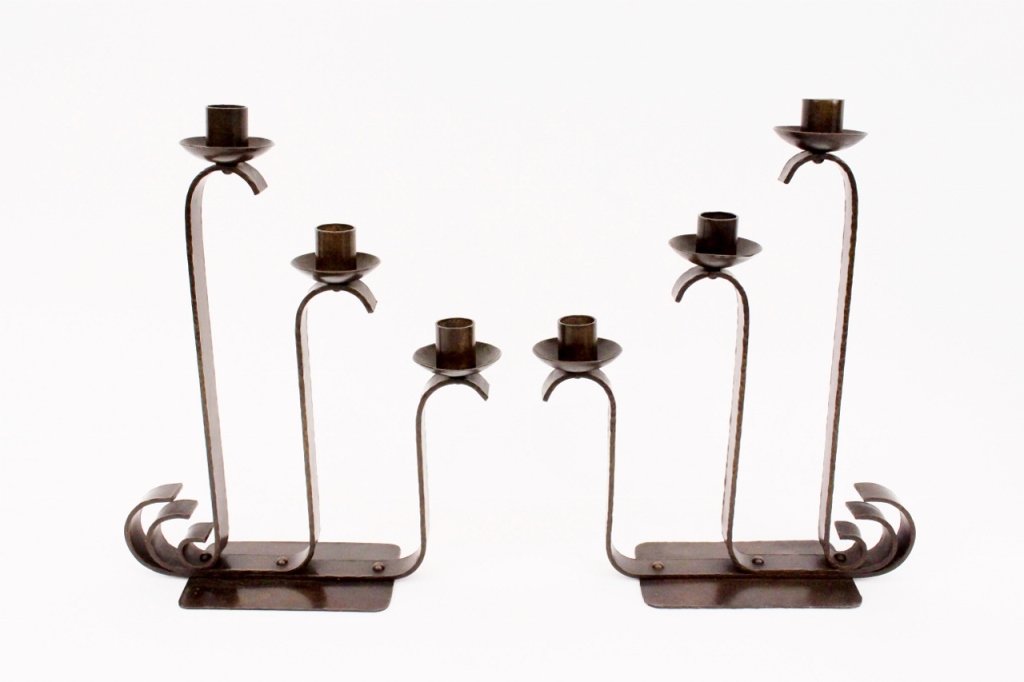 Pair of Arts & Crafts Bronze Three-Arm Candleabras: Two matching Arts & Crafts hand forged patinated bronze candleabras or candlesticks. Each of matching form with three vertical arms with heights of candle shafts descending or ascending with scrolled