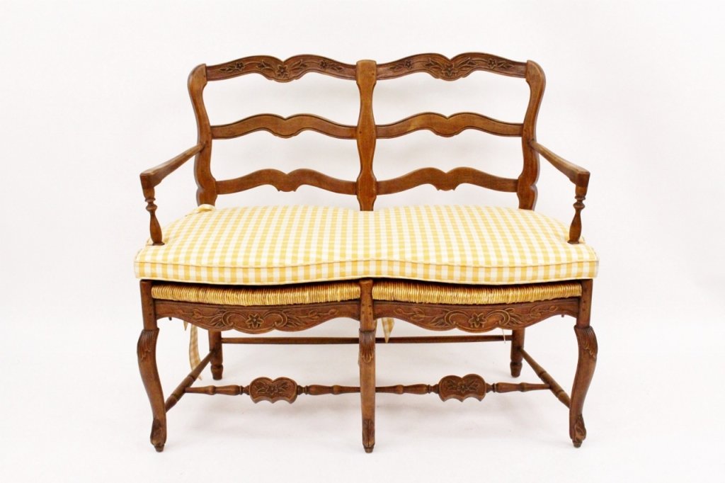 Fruitwood Rush Seat Ladderback Settee: Pierre Deux, 20th century. French provincial style settee composed of a fruitwood frame with ladder back slats decorated with flowers above rush seats. Settee or bench with two armrests and raised on