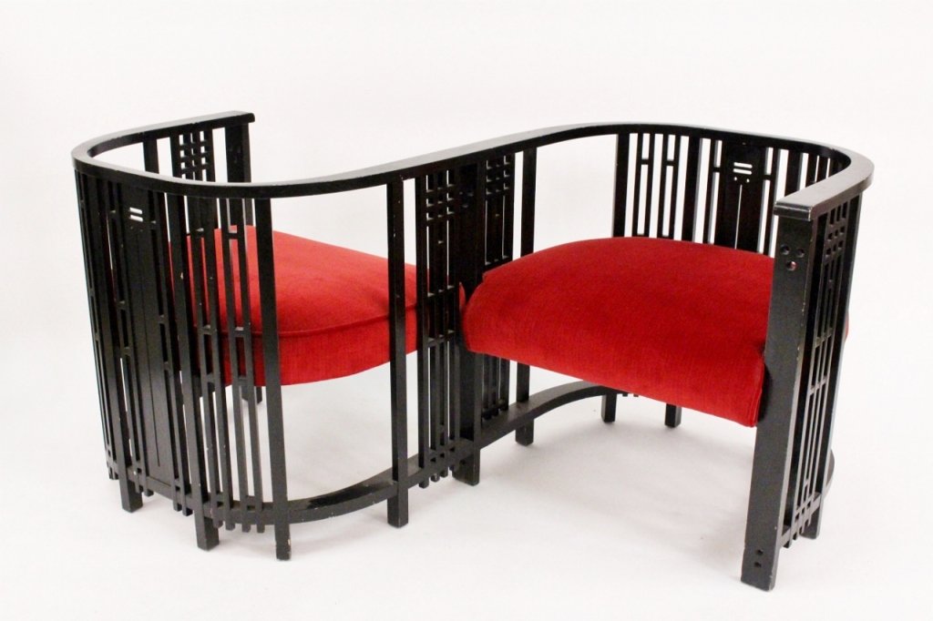 Black Tete a Tete or Conversation Bench: American, 20th century. Black painted wood tete a tete or conversation bench in Prairie School style with geometric slat decoration throughout serpentine curving frame. Seats upholstered in red velvet