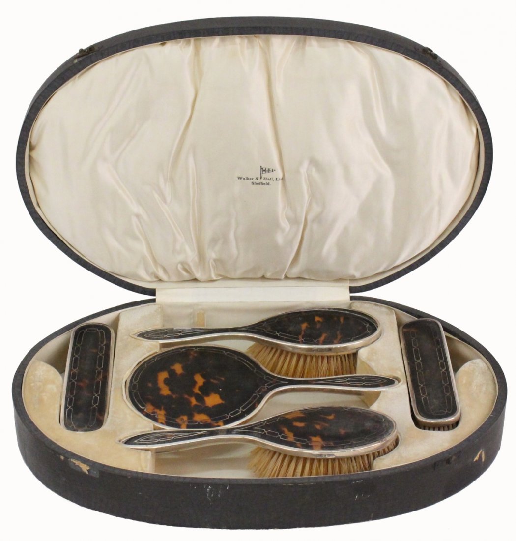 Tortoiseshell & Sterling Five Piece Dresser Set: English, Late 19th/Early 20th century. Five piece dresser set including two handled brushes, two rectangular brushes and a hand mirror each with sterling mounted handles and decoration on tortoise she