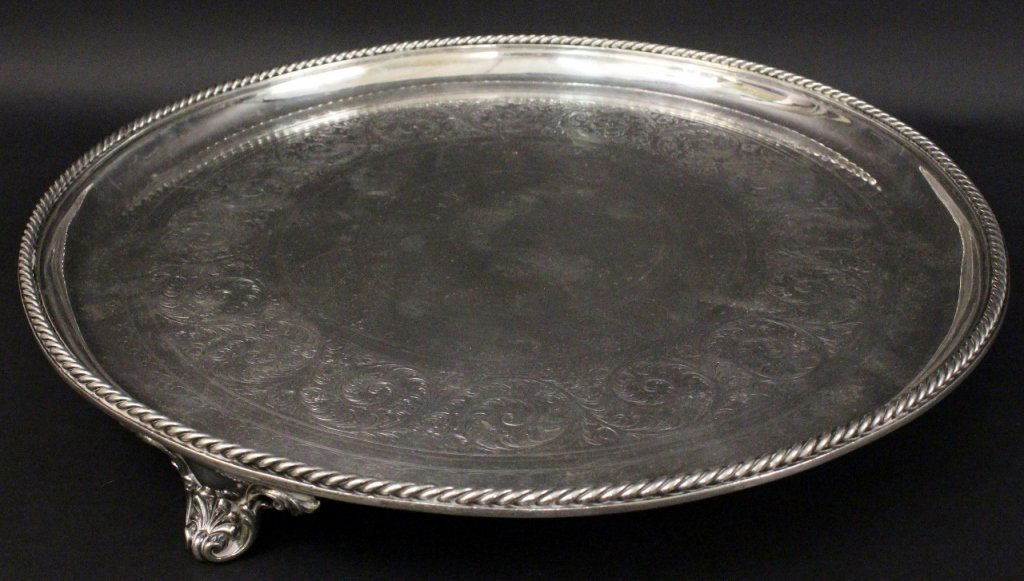 Large Round Elkington Silverplate Tray: Large round silverplated Elkington & Co. tray with etched banded decoration of scrolled foliates and spades in concentric circles in tondo. Tray with rope motif rim and raised on three scrolled foliat