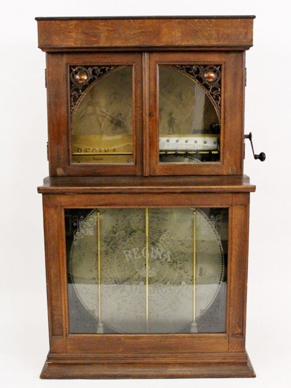 Regina "Corona" Oak Cased Nickelodeon w/12 Discs: American, late 19th century. Regina "Corona, No 34" oak cased upright double combed nickelodeon music player (circa 1899) with glass front with frosted accents on corners and "REGINA CORONA" to showca