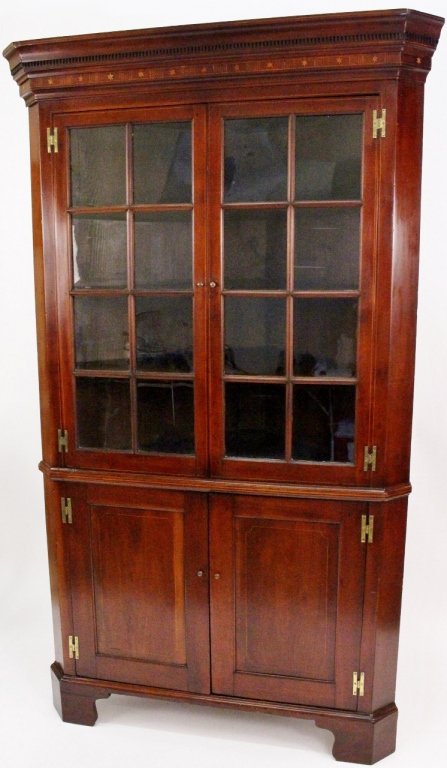 19th C. Inlaid Mahogany Corner Cupboard: American, 19th century. Mahogany wood corner cupboard with inlaid star and stripe motif at top below cornice. Upper portion of cupboard with two hinged doors (each with eight paneled glass front) that