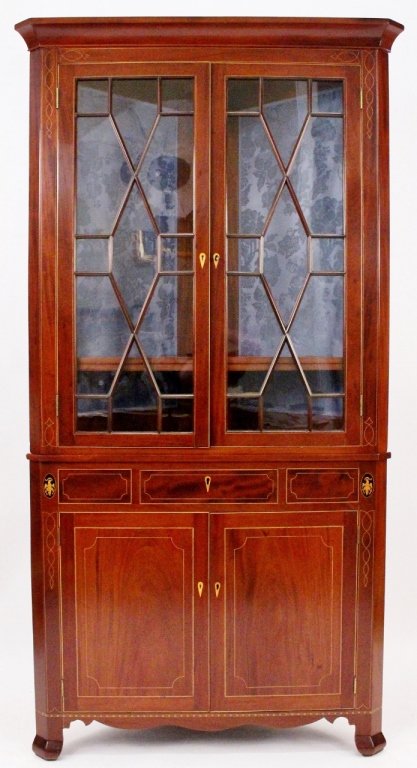 American Federal Style Mahogany Corner Cabinet: American, 19th century. Federal style mahogany and inlaid corner cabinet with cornice top above two hinged and glazed doors that open to shelved storage within (lined with blue brocade fabric). Lower 