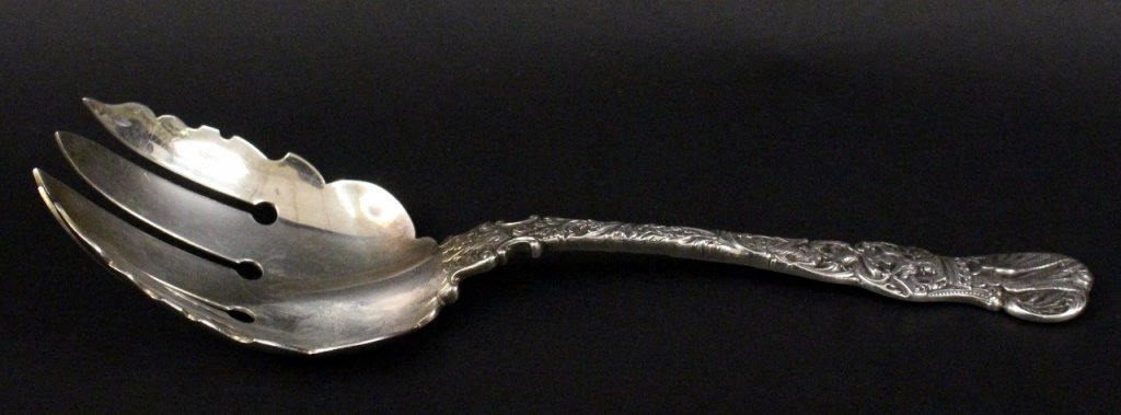 Durgin Sterling Silver Serving Fork: Durgin (American, Late 19th/20th century). Sterling silver serving utensil with five pointed tines with slightly curved spoon form well with ornately decorated handle with "Heraldic" pattern imagery w