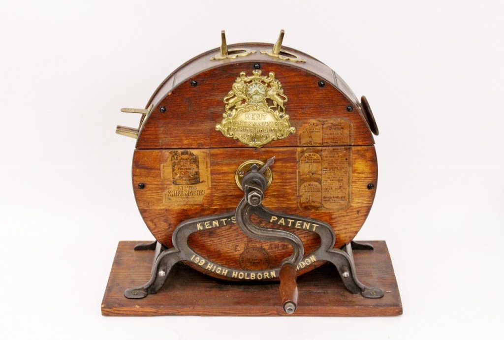 19th C. Kent's Knife Cleaner: English, Late 19th century. Oak cased, iron and brass mounted knife cleaning machine with circular form with wooden handle on rectangular base. Medallion with lion and horse reads "KENT PATENTEE & MAN