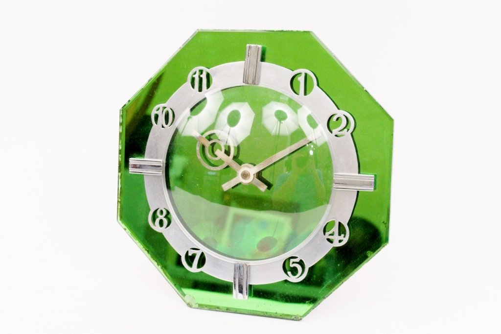 English Art Deco Green Mirrored Table Clock: English, 20th century. Art Deco table clock of octagonal form with mirrored clock face in green hue with chromed numbered dial and stylized hands protected behind glazed dome. Back of clock with colla