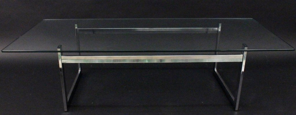 Modern Glass Top Chrome Framed Cocktail Table: 20th century. Modern chrome metal cocktail or coffee table with thick rectangular glass top with rounded corners above a tubular minimal and streamlined chrome base in the style of Milo Baughman. Unma