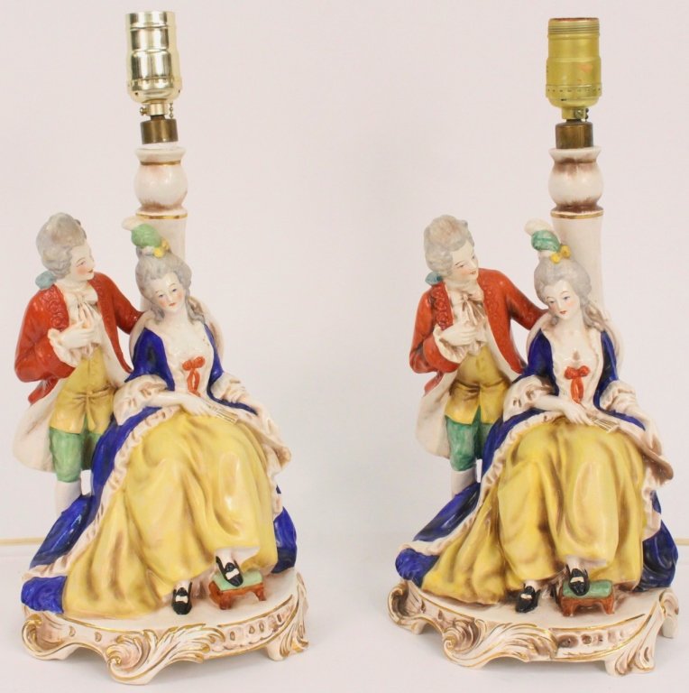 Pair of Figural Porcelain Table Lamps: Continental. 20th century. Marched pair of Dresden style painted porcelain figural table lamps, each depicting a lady and gentleman in 18th century dress, the lady seated with foot on a footstool, in 