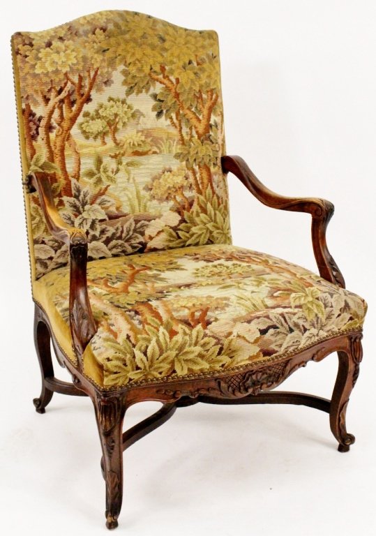 French Walnut & Needpoint Upholstered Armchair: French, Late 19th/Early 20th century. Needlepoint and green velvet upholstered camelback armchair with wooded forest landscape motif on a carved and stained walnut wood frame with arabesque and acanth