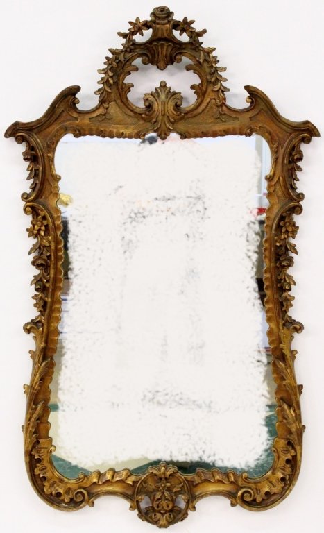 Continental Rococo Style Giltwood Mirror: Continental School, 19th century. Rococo style carved gilt wood and gesso wall mirror of vertical format with leaved, scrolled and floral ornament on frame surrounding looking glass. Overall measures 