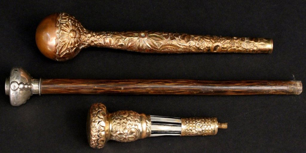 Group of Three Parasol Handles: Group of three parasol handles comprising of bamboo silver mounted handle with dark bamboo wood shaft; an antique rolled gold handle with floral repousse motif and mother of pearl and ebony striped ba