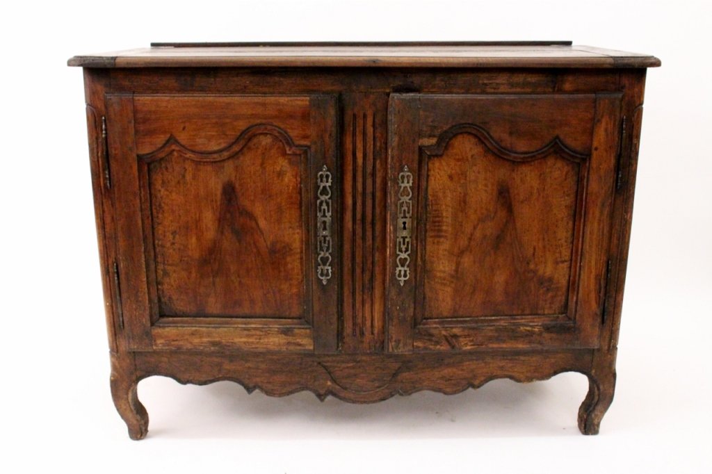 18th Century French Provincial Two Door Buffet: France. 18th Century. French Provincial oak carved two door buffet with two raised and recessed paneled cupboard doors with original locking mechanism and key over a carved scalloped apron on cabriole