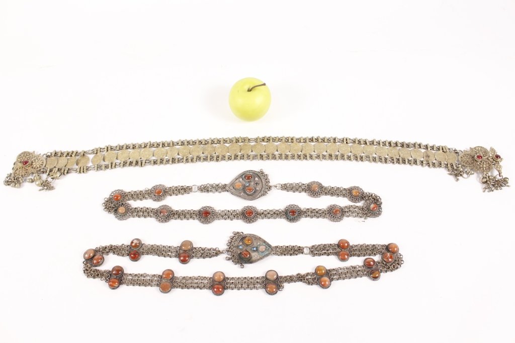 Group of Three Middle Eastern Belts: Collection of three different Middle Eastern (likely Saudi Arabian) ladies belts comprising of one with gold tone with 34 coin discs on strap with red glass accented buckles, dangling bells for dancin